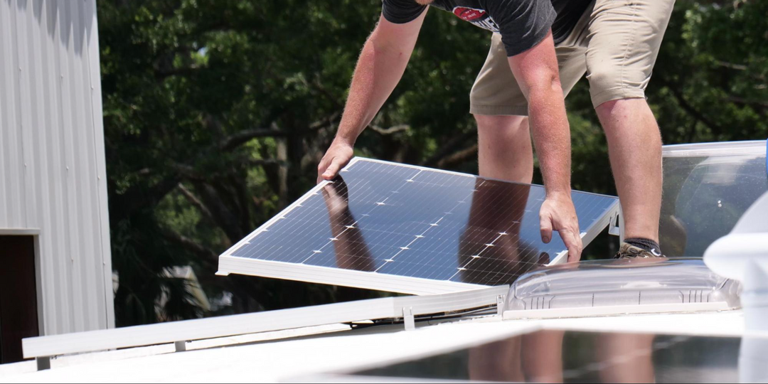 A man installing solar panels on the roof