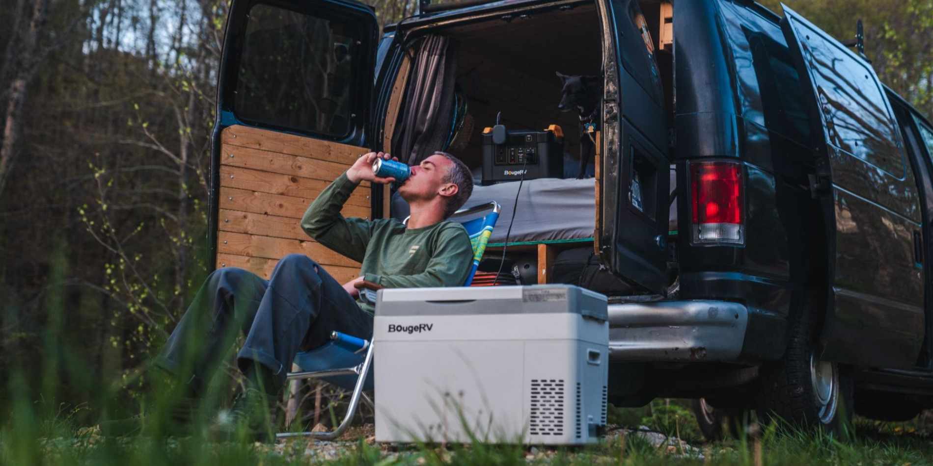 A man sits and drinks a beverage with a BougeRV 12V fridge in front of him