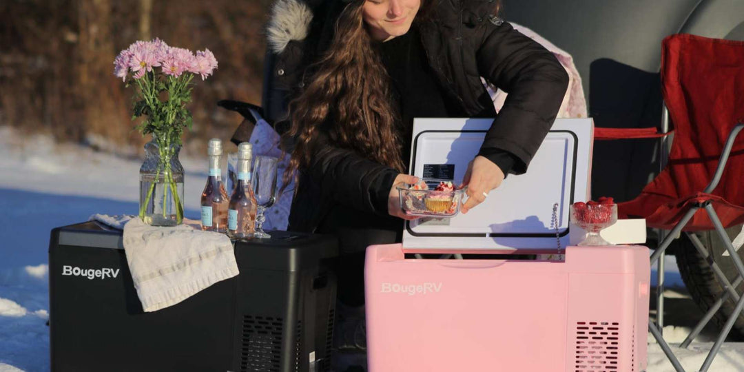 A woman camping in the snow and using BougeRV’s pink and black portable power station