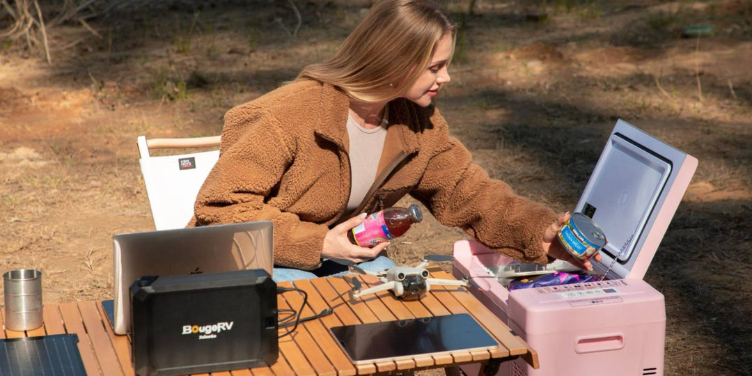 A young lady camping with a BougeRV pink portable fridge and 240Wh JuiceGo portable power station