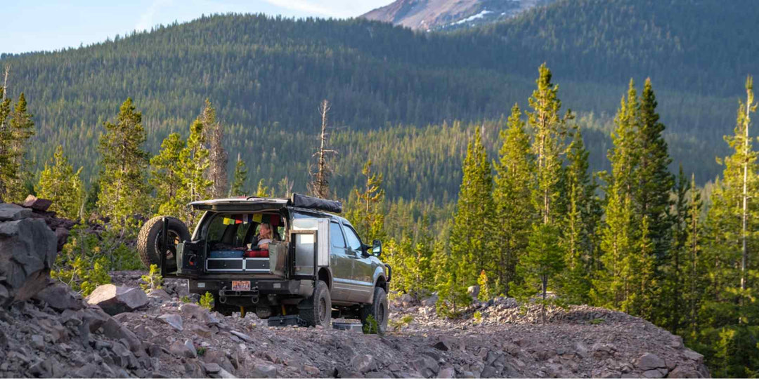 An overlanding vehicle parking on rocky ground with a stunning mountain backdrop-1